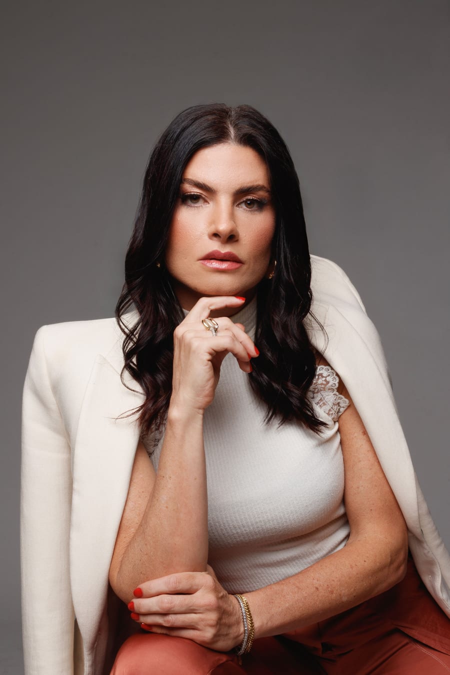 Stéfanie Càssis de blazer branco, com a mão no queixo